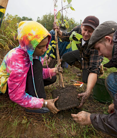Green Mountain College students plant trees to form a riparian buffer along the Poultney River.
