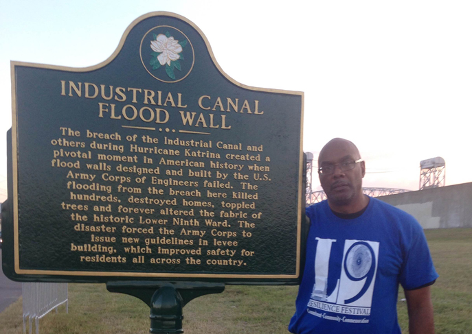 Aaron Mair at Industrial Canal flood wall sign.