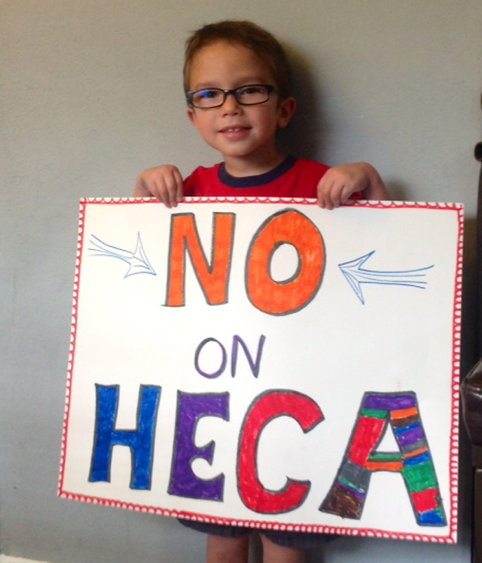 Nikolas Leon holding up his homemade "No on HECA" sign