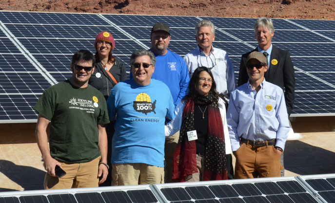 Sierra Club Utah Chapter Chair Marc Thomas, in blue shirt, solar developers, and Moab City Council members celebrate the completion of Moab City Hall's rooftop solar project