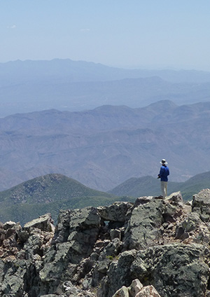 Hiker peers out at the southeast horizon from Four Peaks