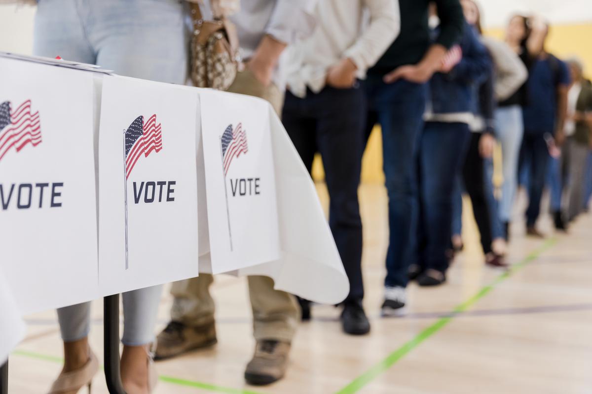 iStock photo of "a low angle view of a long line of people waiting to vote in the elections."