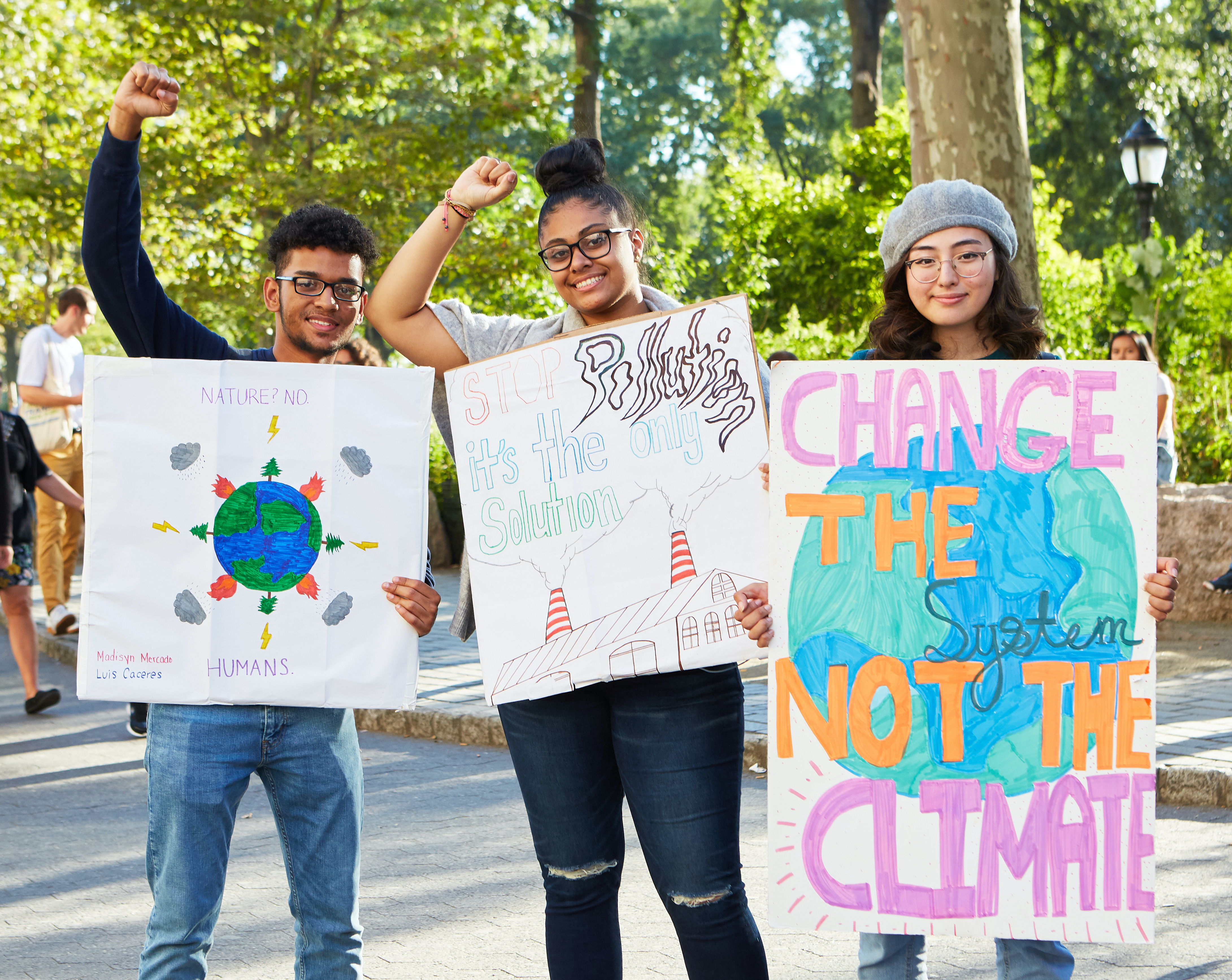 Three teen environmental activists holding posters