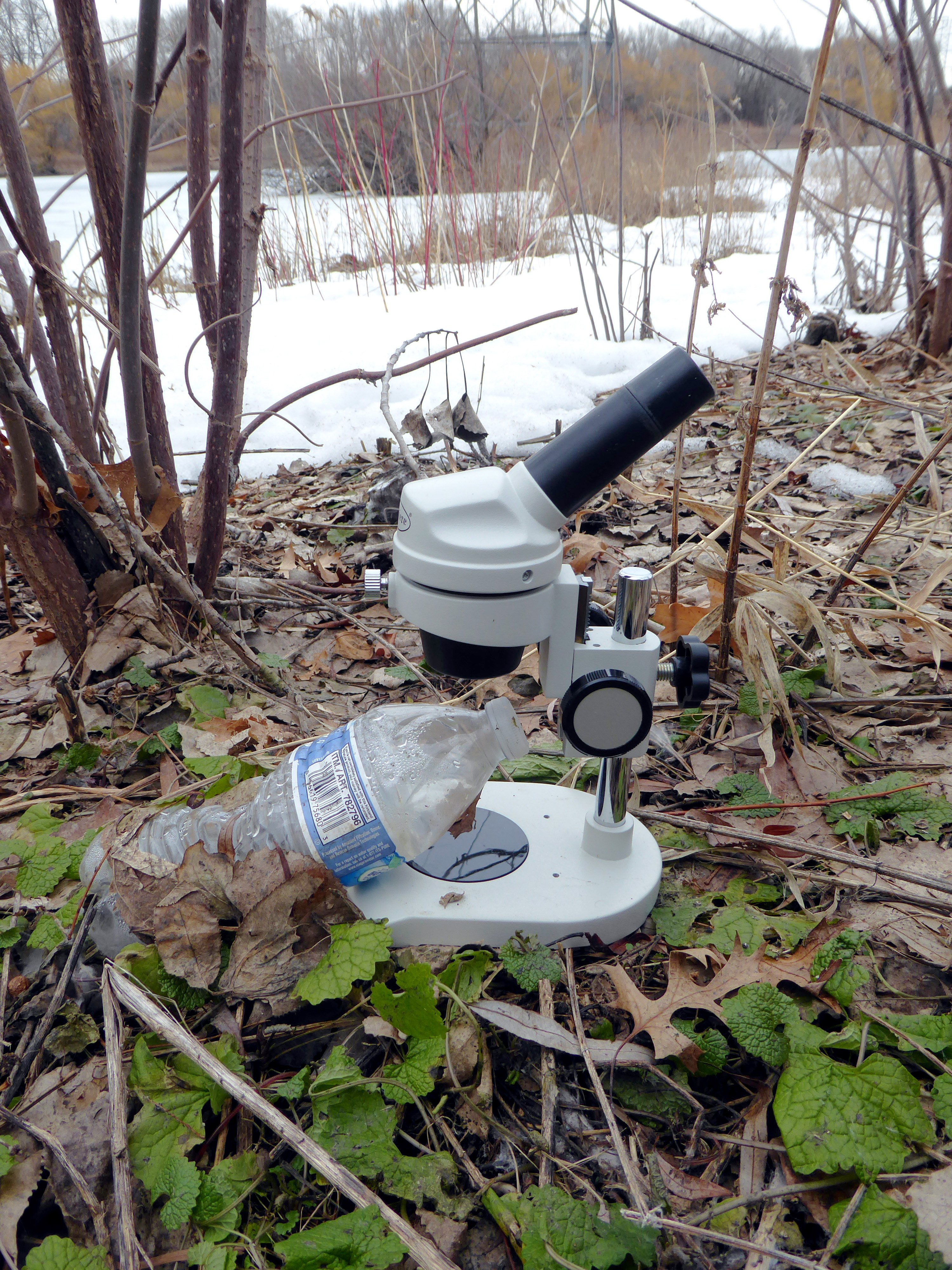 photo of empty plastic bottle on a microscope in the woods