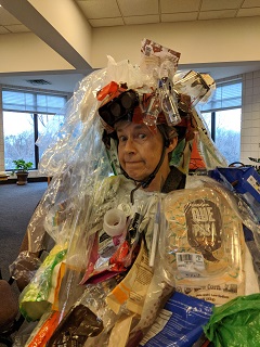 Photo of Zero Waste Team member, Josie Winship, wearing plastic litter she found in her neighborhood and some of her own plastic that she finds hard to avoid.