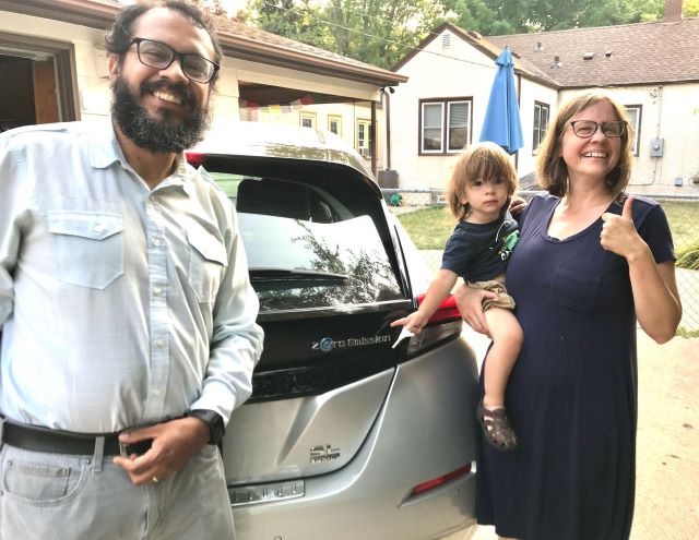 photo of family smiling in front of their new electric car