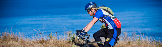 Male bike rider on coastal route; blue ocean in background