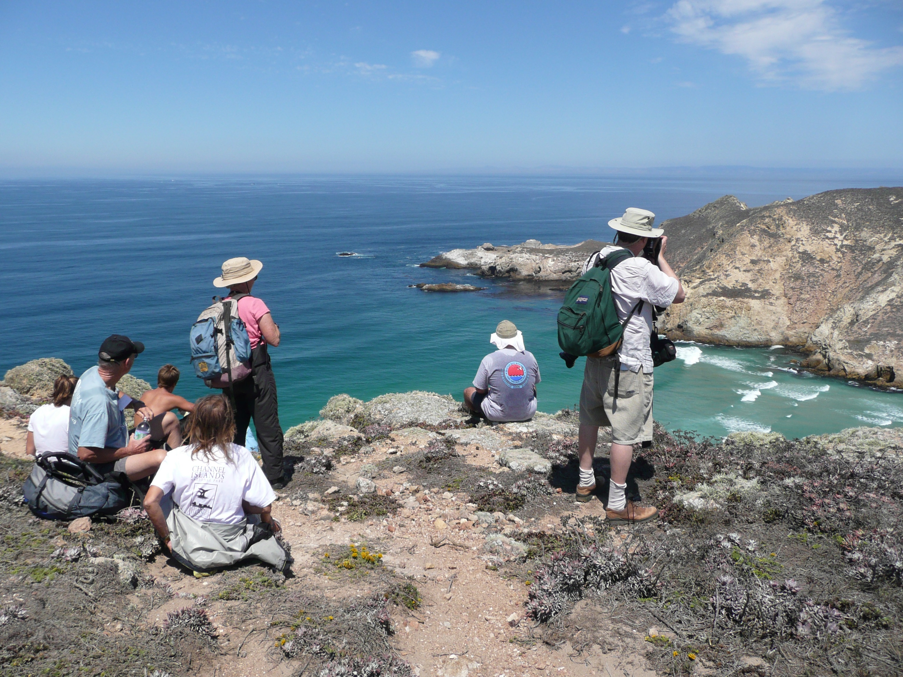 Hikers resting at overlook of island and blue ocean on a sunny day