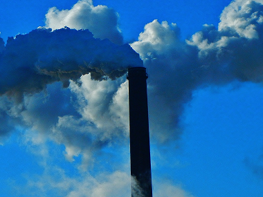 Smoke pouring from industrial stack in blue tones