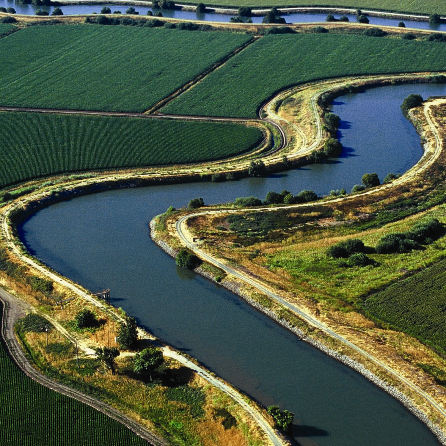 Blue Delya canal winding through green crops