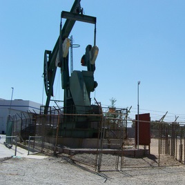 Oil pump behind a fence under a blue sky