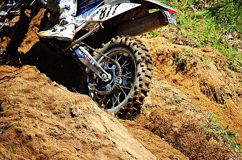 Rear of off-road motorcycle cutting a trench in a hillside