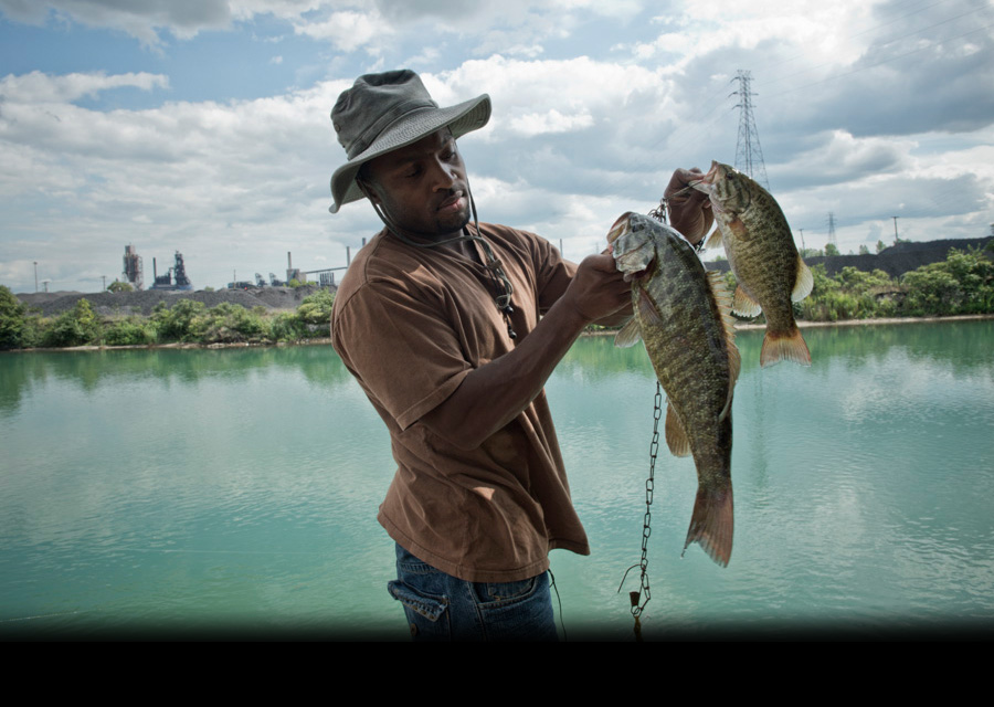 Just across the water from the intensely industrialized Zug Island, Kevin Morris shows off the bass he caught in a Detroit River canal. "Driving here, it's like entering another world," said Morris, who lives in Detroit. "It's almost what a Third World co