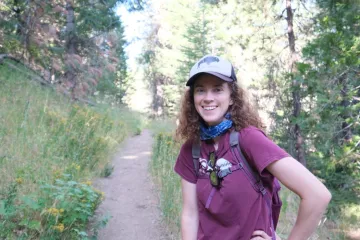 Executive Committee member Kate Wilkins standing on a hiking trail, smiling at the camera.