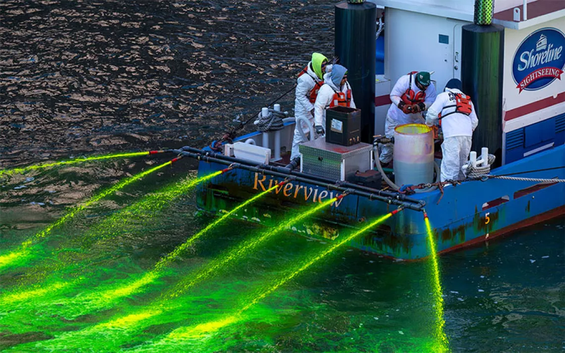People on a boat spray green dye into the Chicago River