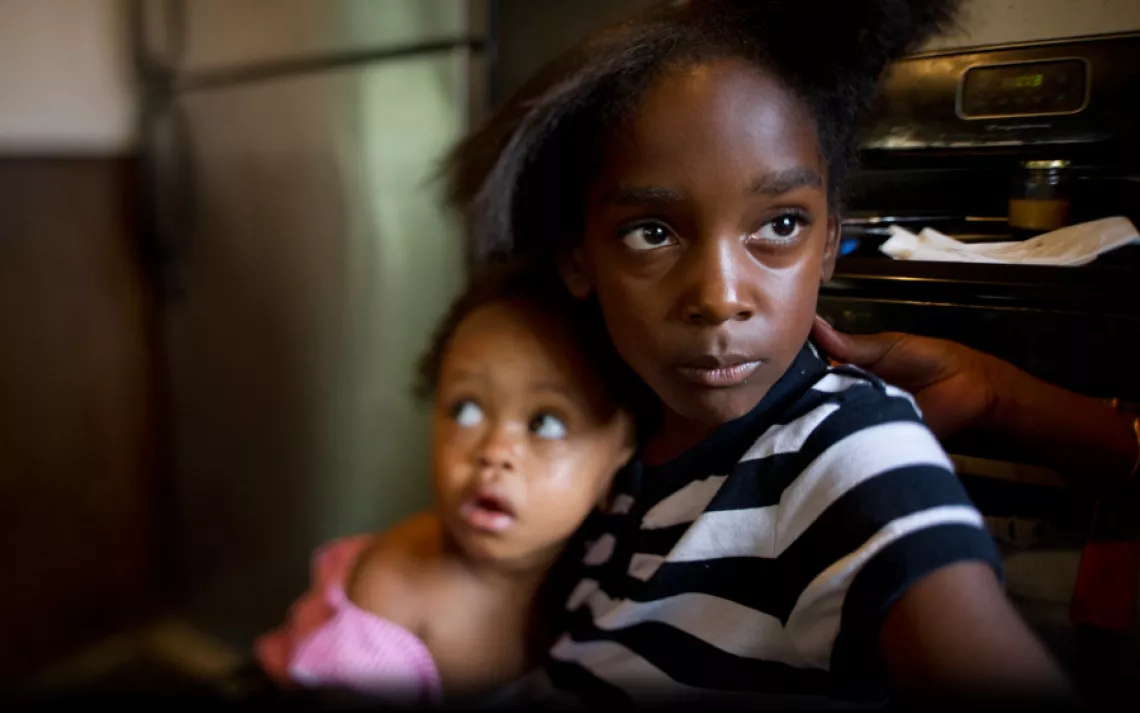 Marianna Hildreth, 7, holds her cousin Mariyah McGhee, 1, who has asthma, in their grandmother's kitchen in River Rouge, Michigan. | Ami Vitale/Panos Pictures