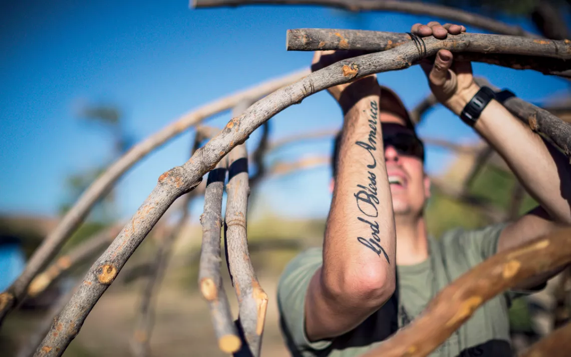 A man with a "God Bless America" tattoo helps erect a sweat lodge near the San Juan River in southeastern Utah.