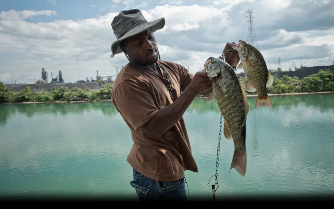 Just across the water from the intensely industrialized Zug Island, Kevin Morris shows off the bass he caught in a Detroit River canal. "Driving here, it's like entering another world," said Morris, who lives in Detroit. "It's almost what a Third World co