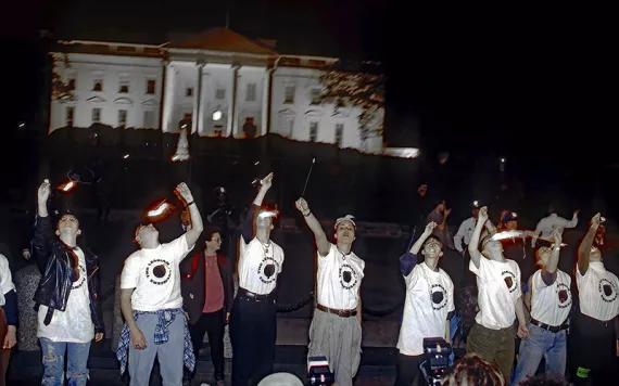 Women in white t-shirts eating fire in front of the White House in the night.