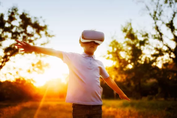 Young boy wears VR headset as he ventures outdoors.