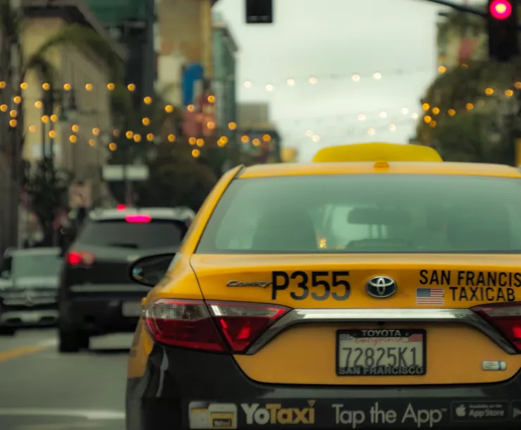 The back of a yellow San Francisco taxi cab against a blurred city background