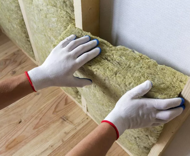 Close-up of worker hands in white gloves insulating rock wool insulation staff in wooden frame for future walls for cold barrier.