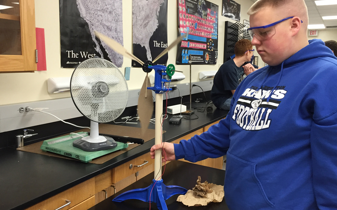 A high school student checks out a miniature wind turbine.