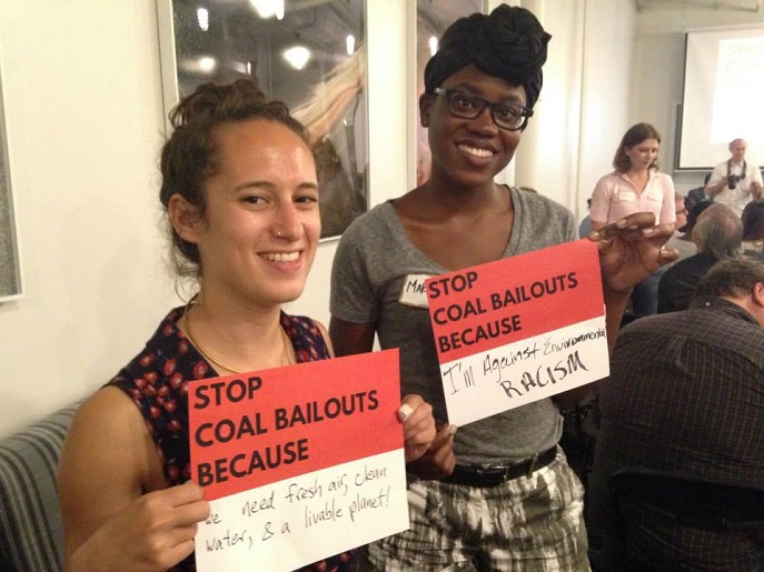 Two volunteers hold up signs explaining why they support ending coal bailouts. 