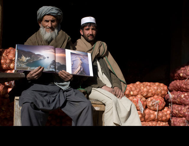 Hazmatullah (left), 61, with his son Rahmatullah at their onion shop at a produce market in Kabul. After they sell their onions, they will return to their village in the Nangarhar province in east Afghanistan. Hazmataullah displays photos of Potato Harbor