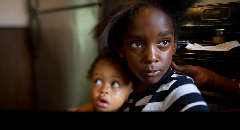 Marianna Hildreth, 7, holds her cousin Mariyah McGhee, 1, who has asthma, in their grandmother's kitchen in River Rouge, Michigan. | Ami Vitale/Panos Pictures