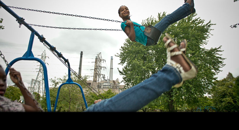 Nikeya Aaron, 9, enjoys a moment of weightlessness in Belanger Park, which is sandwiched between the coal-fired River Rouge Power Plant and a massive steel mill. | Ami Vitale/Panos Pictures