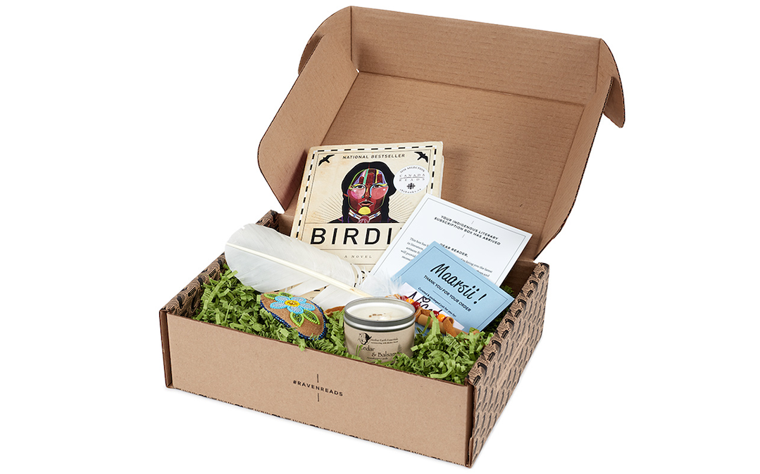A gift box containing a book, feather, and candle