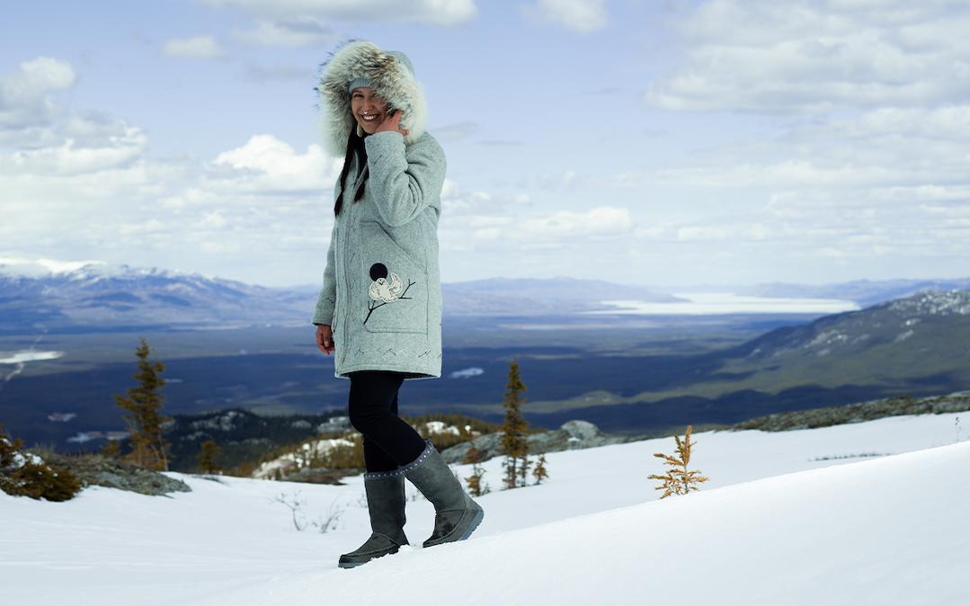 A person walks through the snow wearing tall mukluk boots