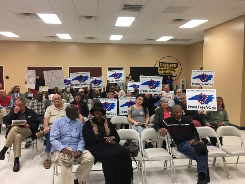 Meeting attendees show their opposition to the ACP