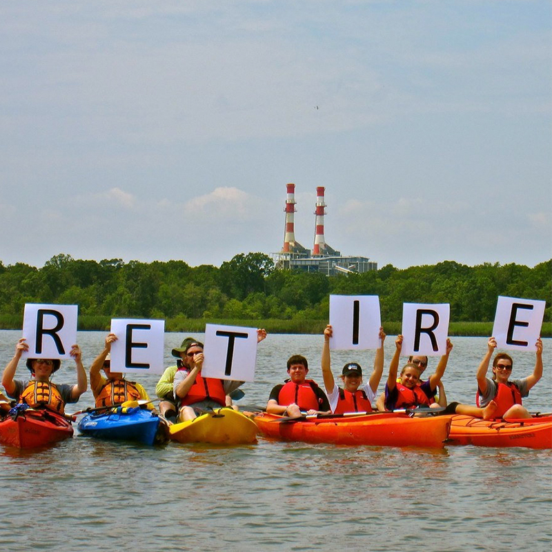 Protesters in kayaks holding signs that spell RESIST