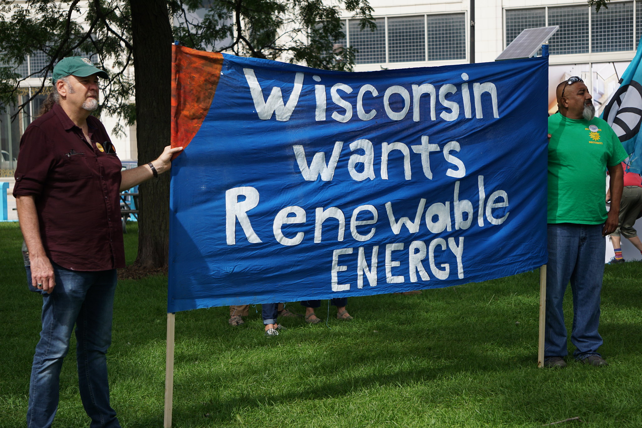 Two volunteers hold a sign that reads "Wisconsin Wants Renewable Energy"