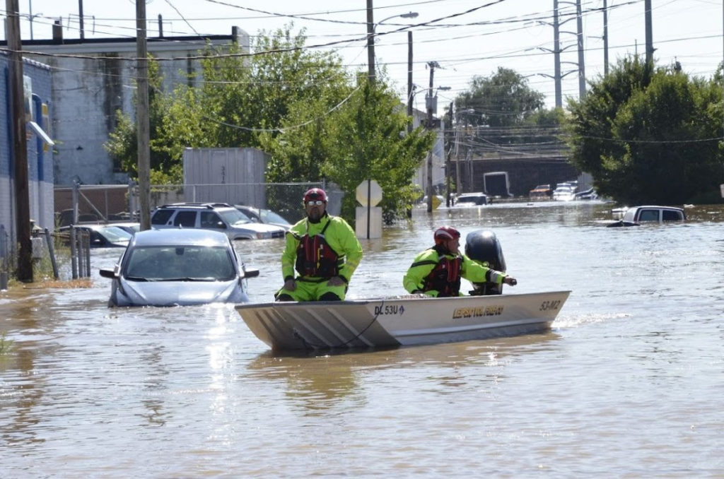 Hurricane Ida floods wilmington, two men in yellow in a boat on flooded downtown street