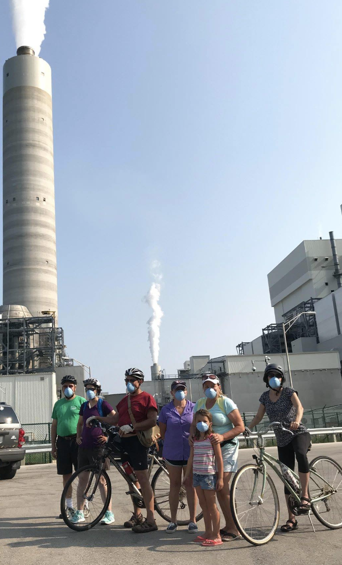 Bikers protest in front of the Oak Street coal plant wearing protective masks