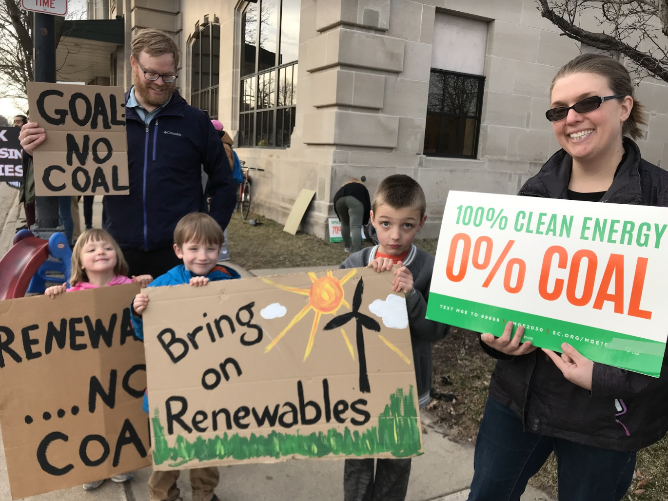 Protesters (including children) holding up signs opposing coal and demanding cleaner sources of energy