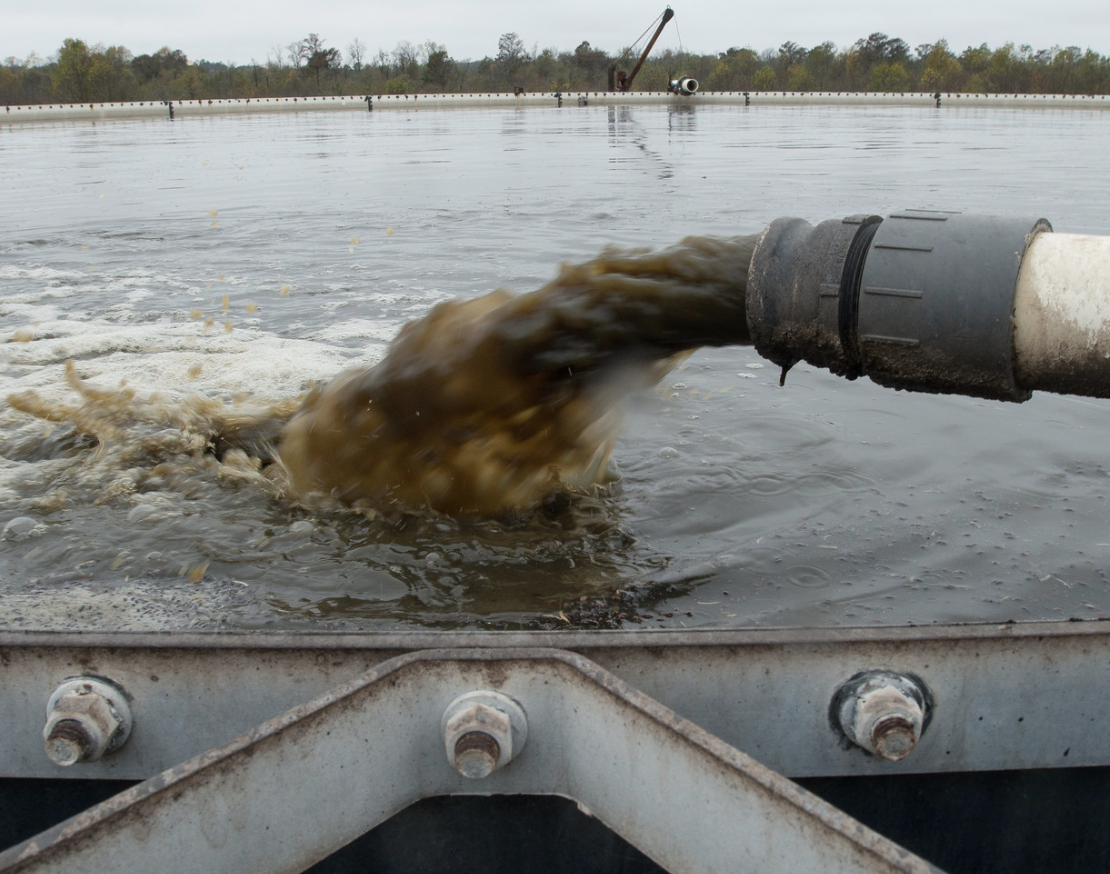 Pipe expelling liquified manure into waste lagoon
