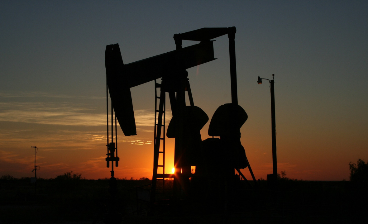 A piston pumps oil at an oil well at dusk