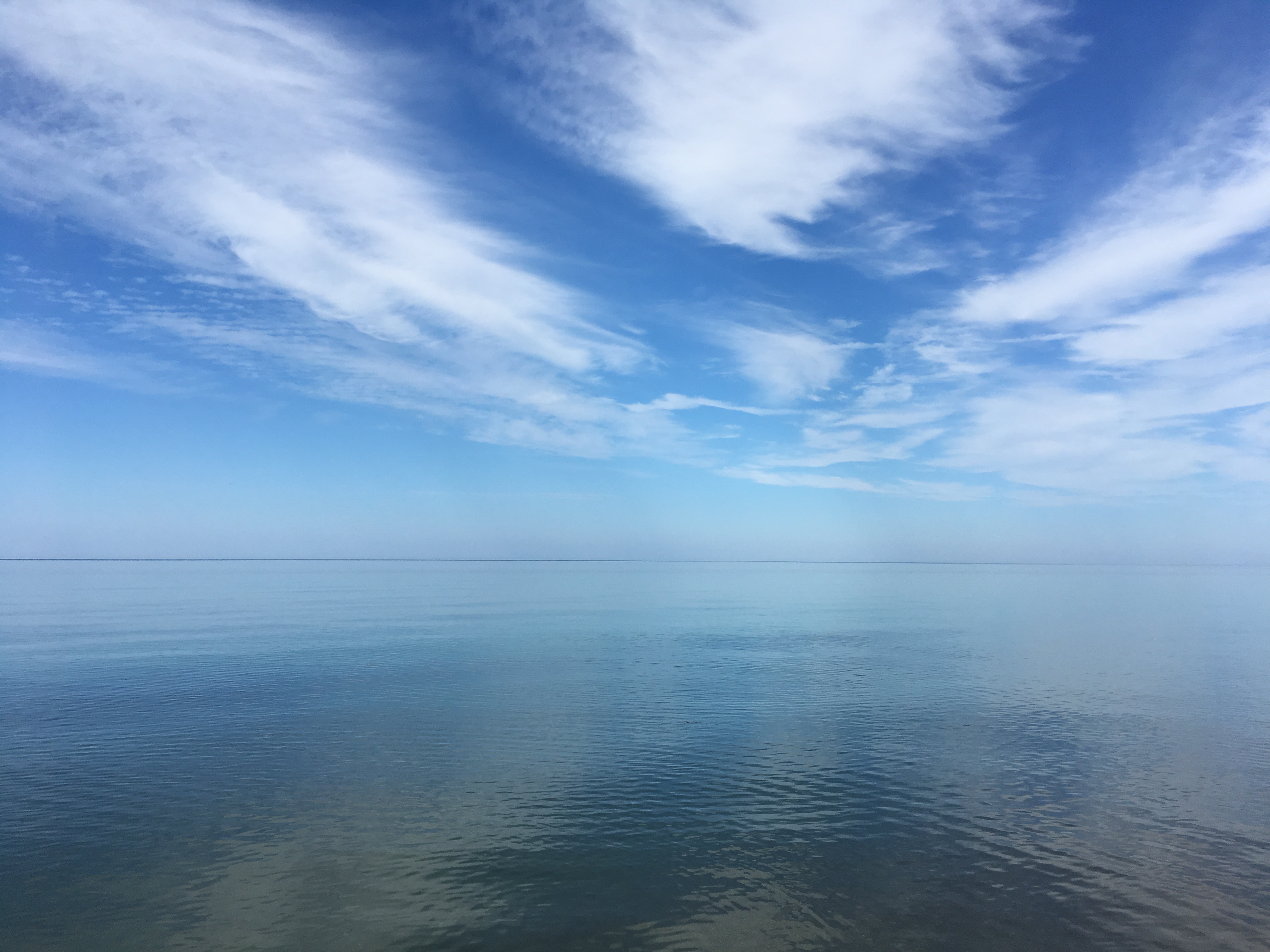 The blue waters of Lake Michigan on a calm day with partly cloudy skies
