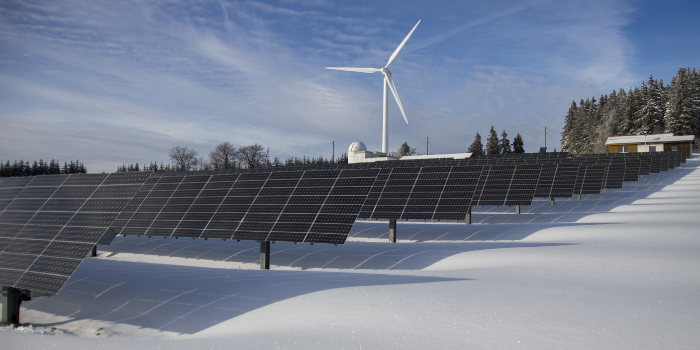 Solar panels and a wind mill on a snow-covered field
