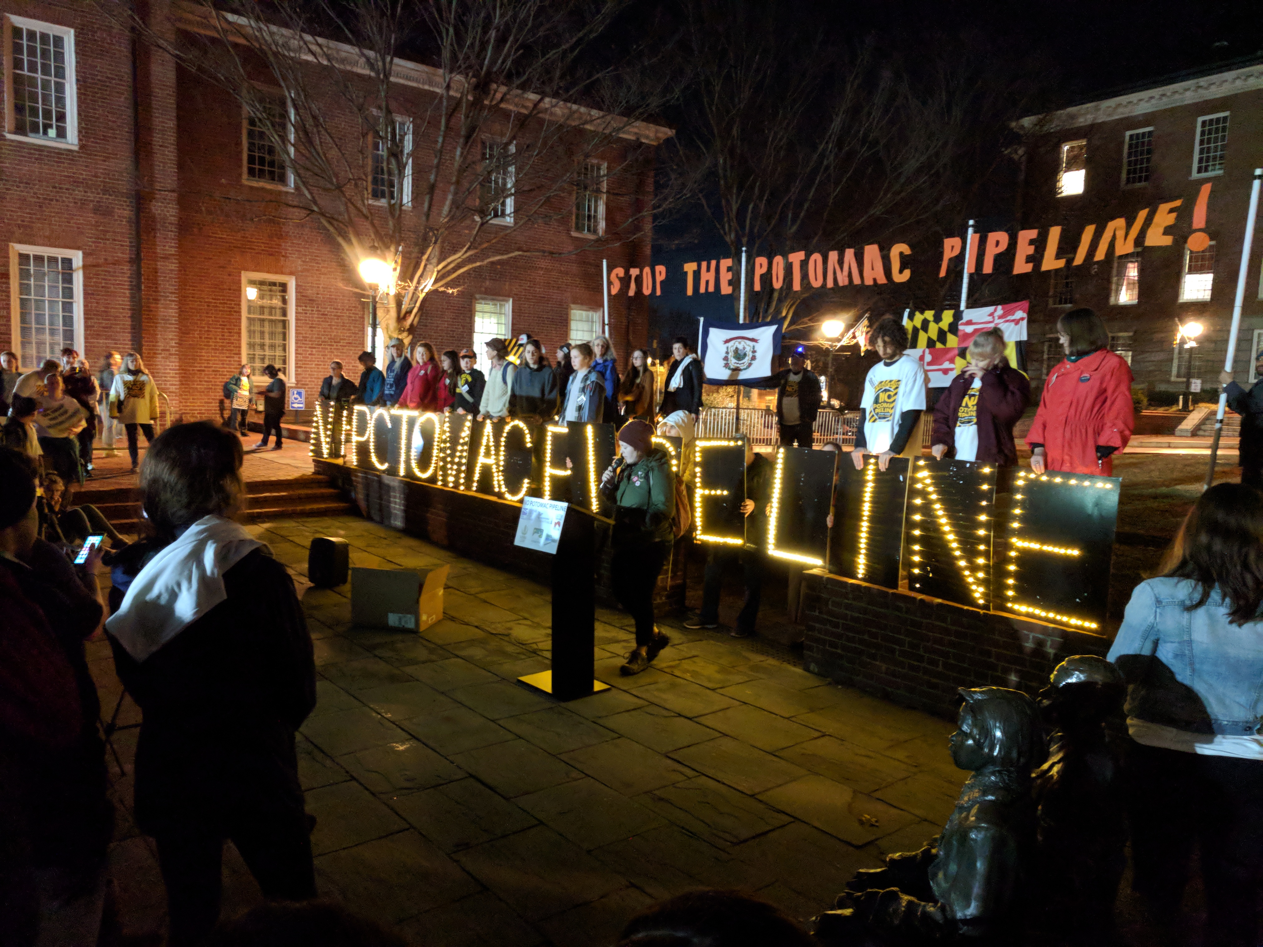 Deirdre Lally, standing at podium in front of State house