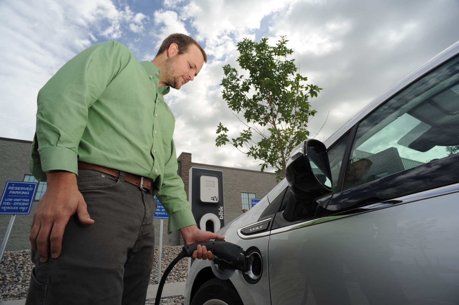 Person plugging an electric vehicle in to charge
