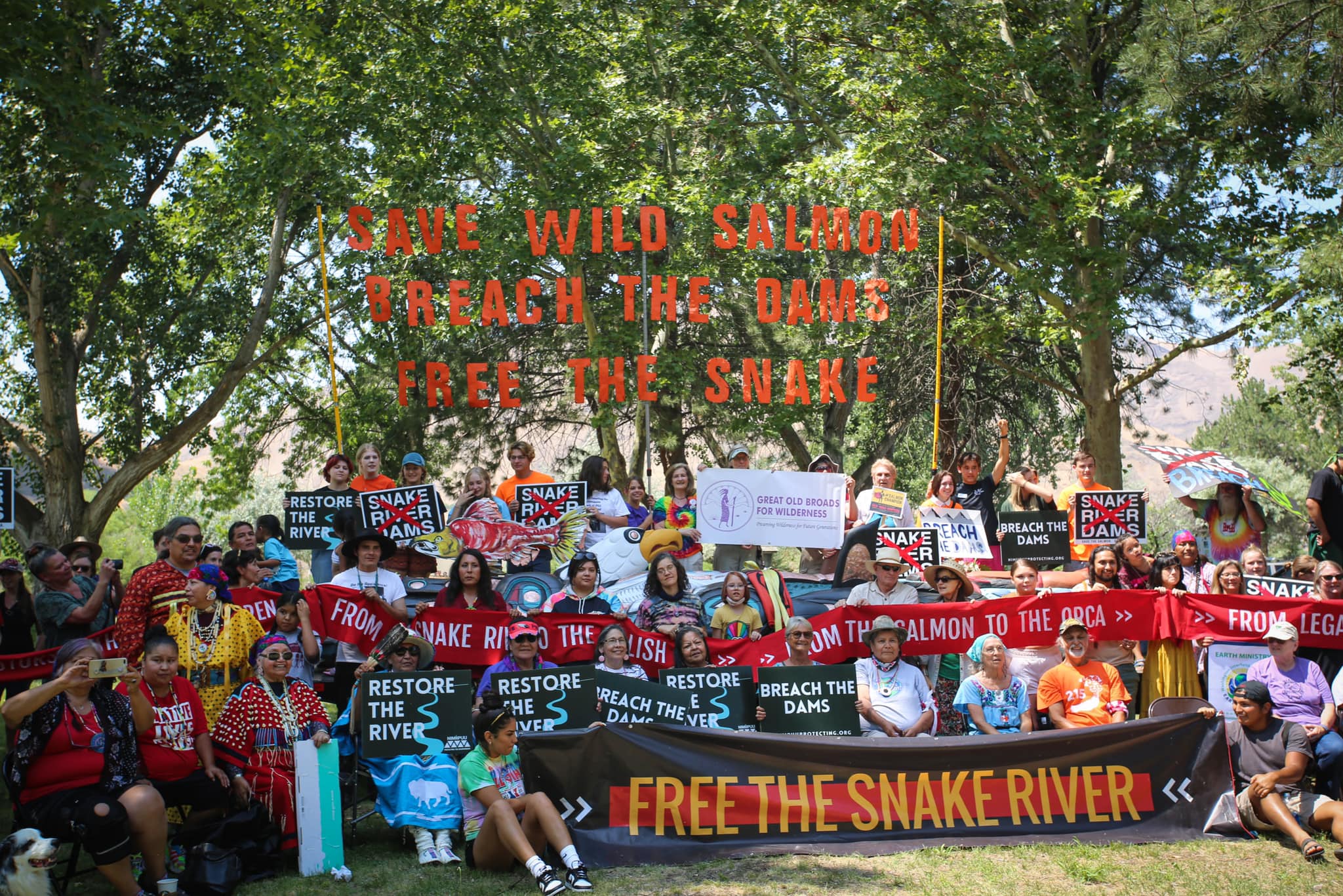 Lots of people (Native and non-Native) gathered for a photo holding signs and banners that say Save Wild Salmon, Breach the Dams, Free the Snake River