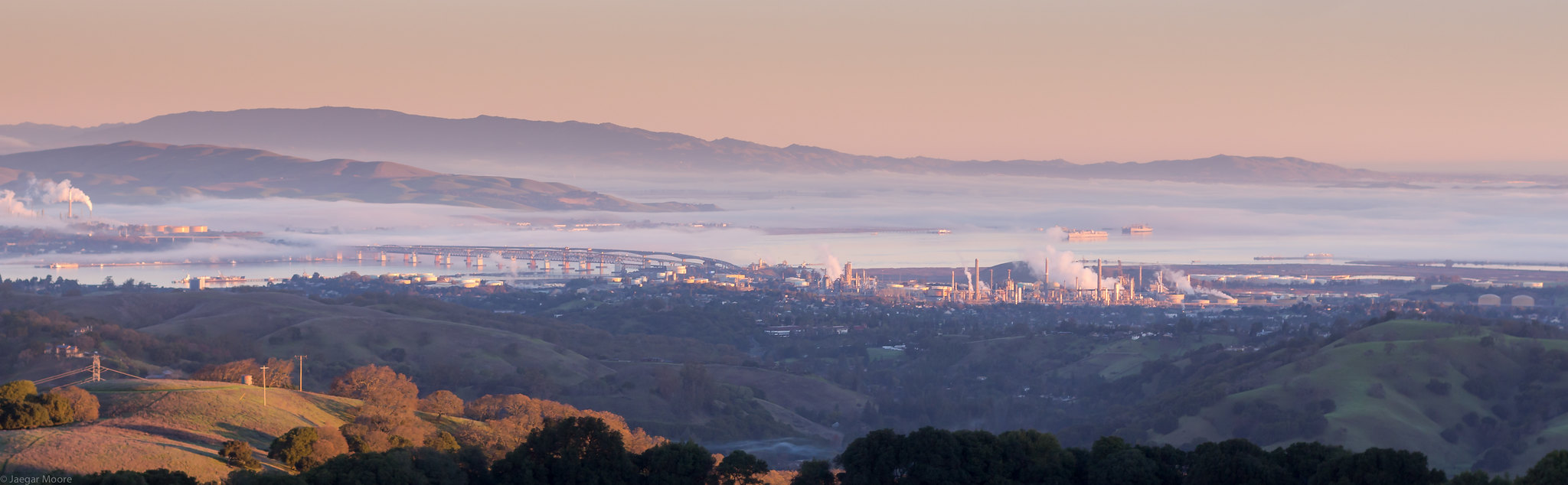 Landscape of Martinez with refinery in the distance, blowing smoke in the air.