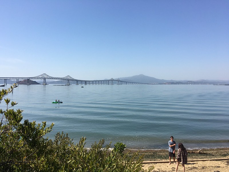 People playing on the beach and kayaking in the Bay along the Point Molate shoreline