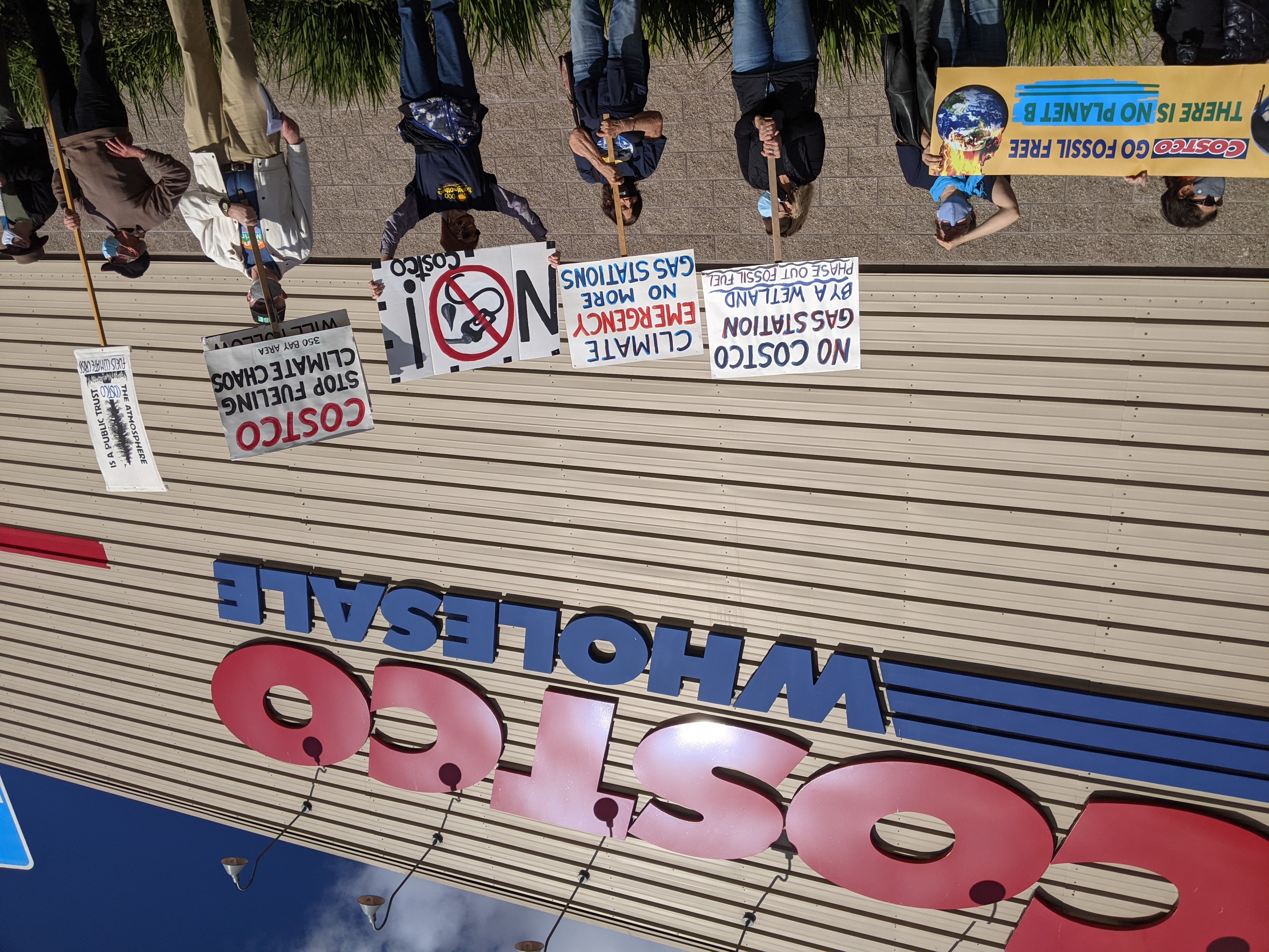 Activists speaking and holding signs at rally against Novato gas station.