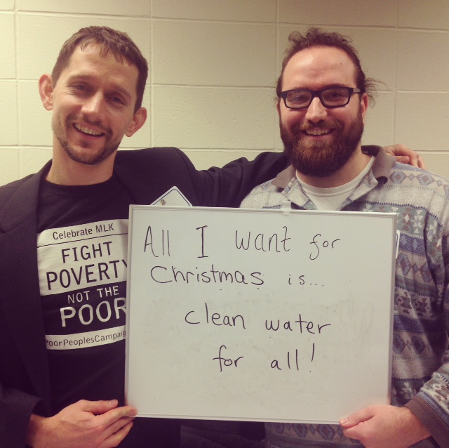 Participants at HEC holding a sign saying "all I want for Christmas is clean water for all"